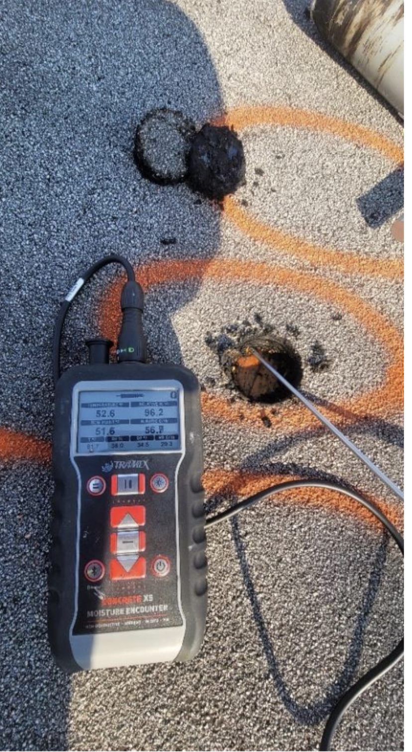 Tramex moisture encounter meter with probe inserted into flat roof membrane showing elevated moisture readings at a Chicago flat roof inspection